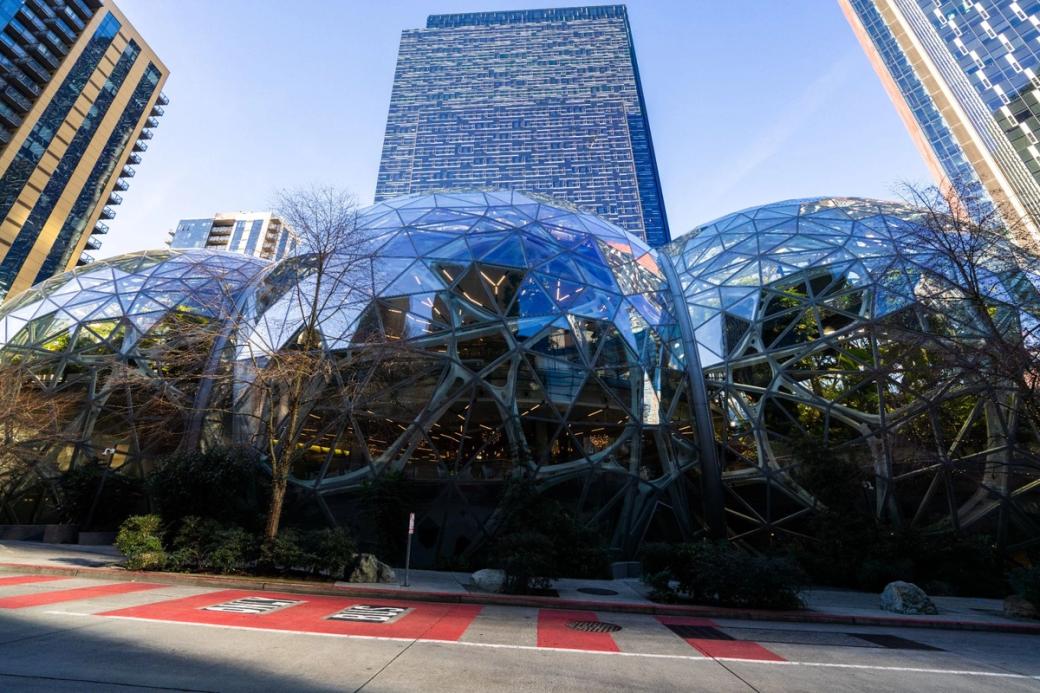 Photograph showing three glass domes at Amazon HQ in South Lake Union with a tall glass skyscraper in the background and one on the left and right of the domes as well