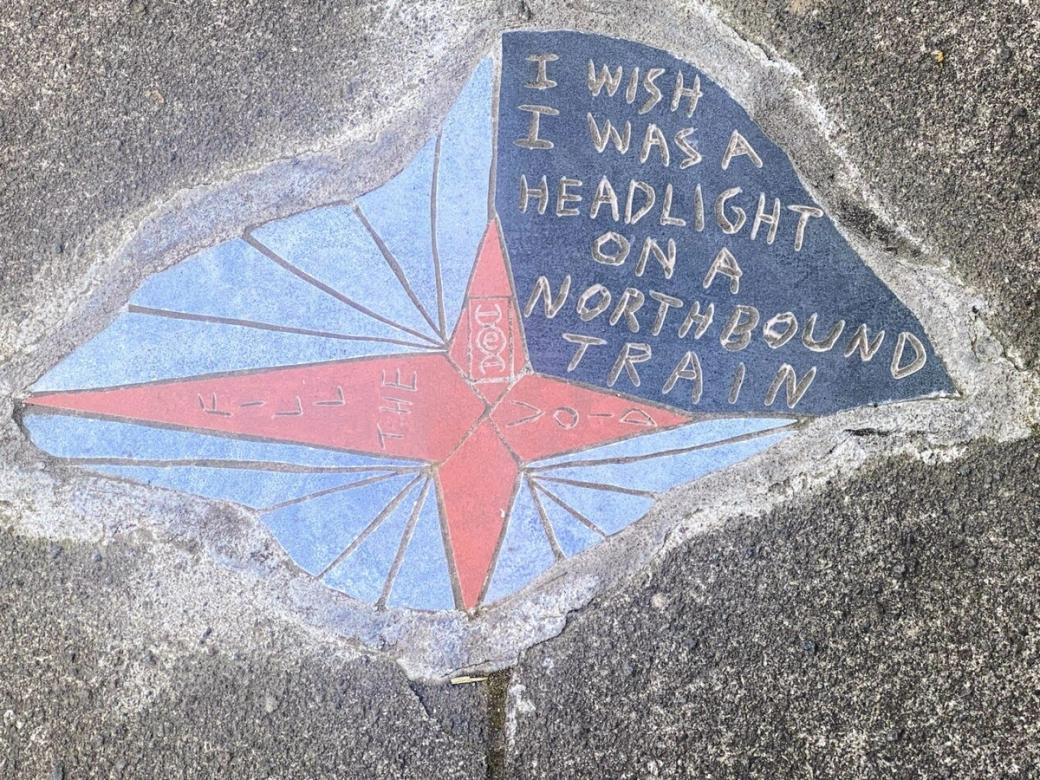 A blue and red sidewalk mosaic that reads “I was a headlight on a northbound train” and “Fill the Void”