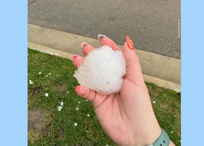 A well-manicured hand holding a giant hailstone.