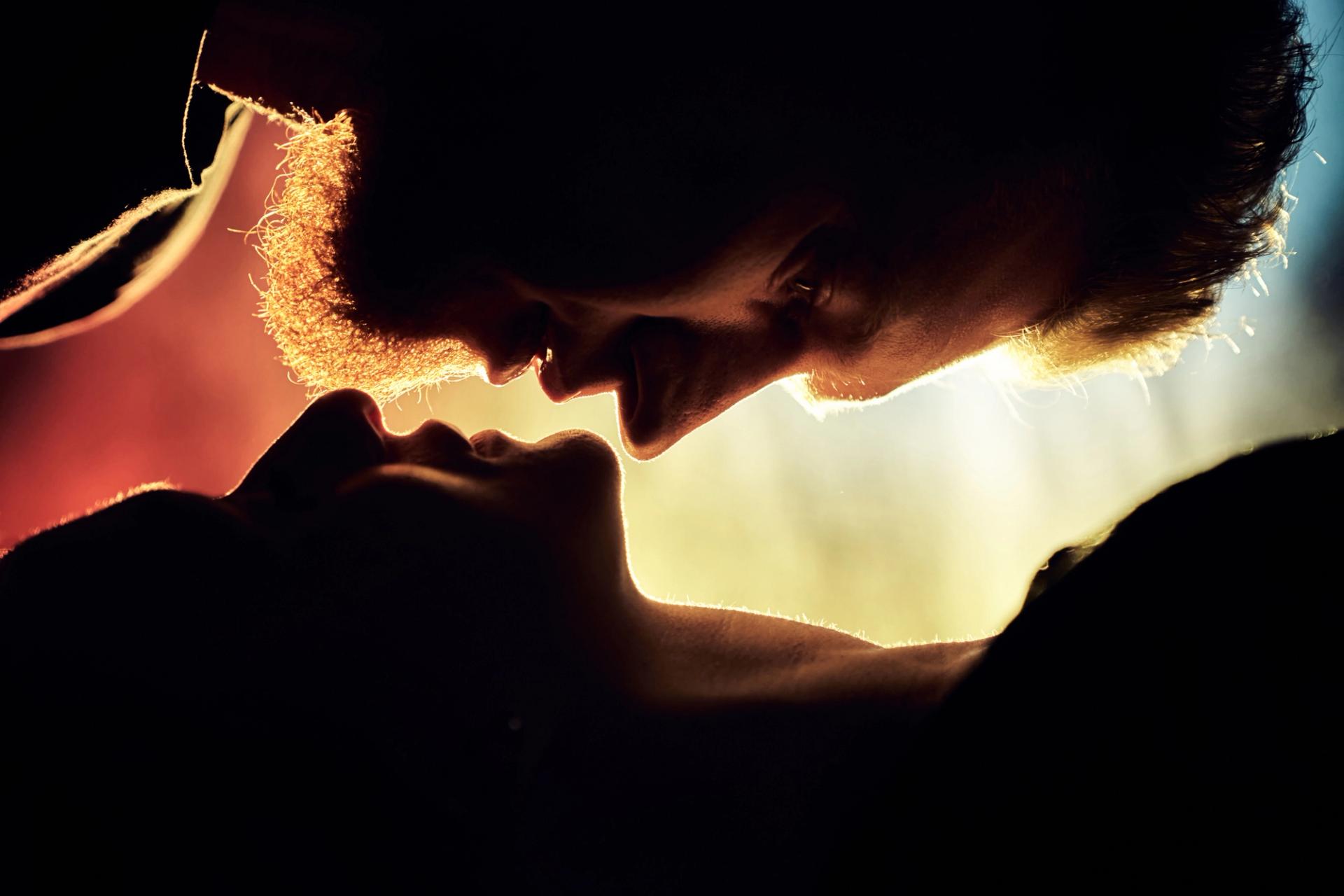 Two people nearly kissing in a dark room.