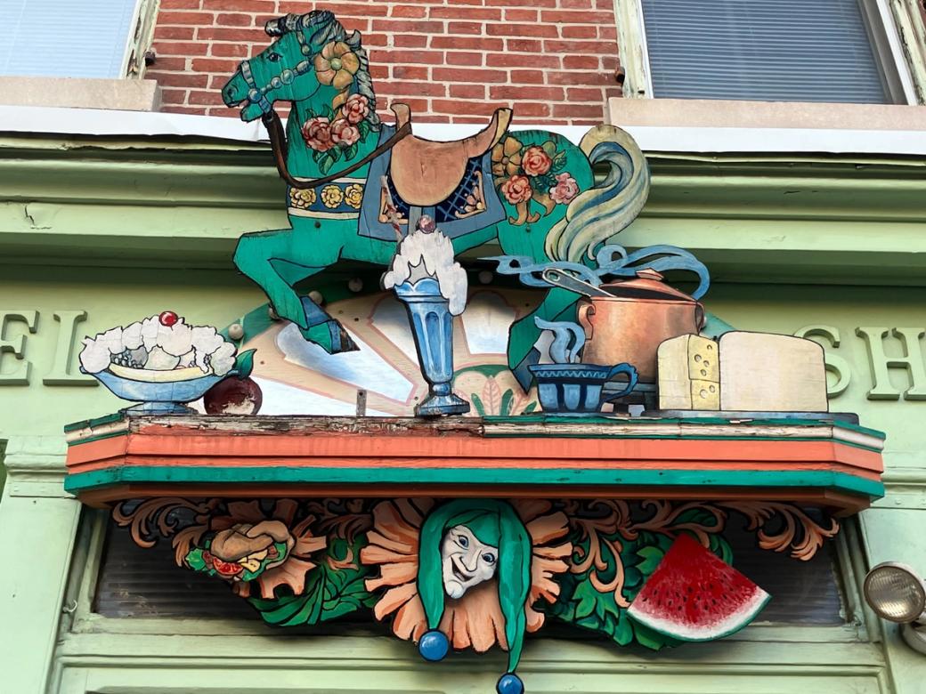 A wooden display of a horse and jester among sundaes, fruits, and cheese