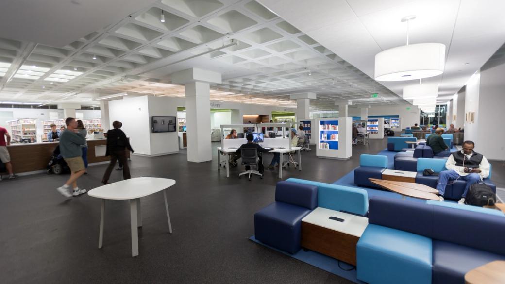 The interior of a library with blue couches.