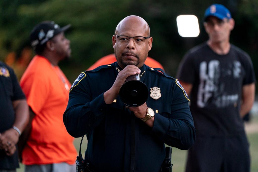 An image of Shon Barnes in police uniform holding a megaphone