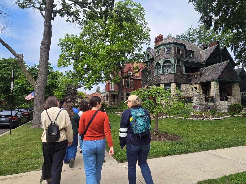 A group of people walking on a sidewalk in a neighborhood on a sunny day