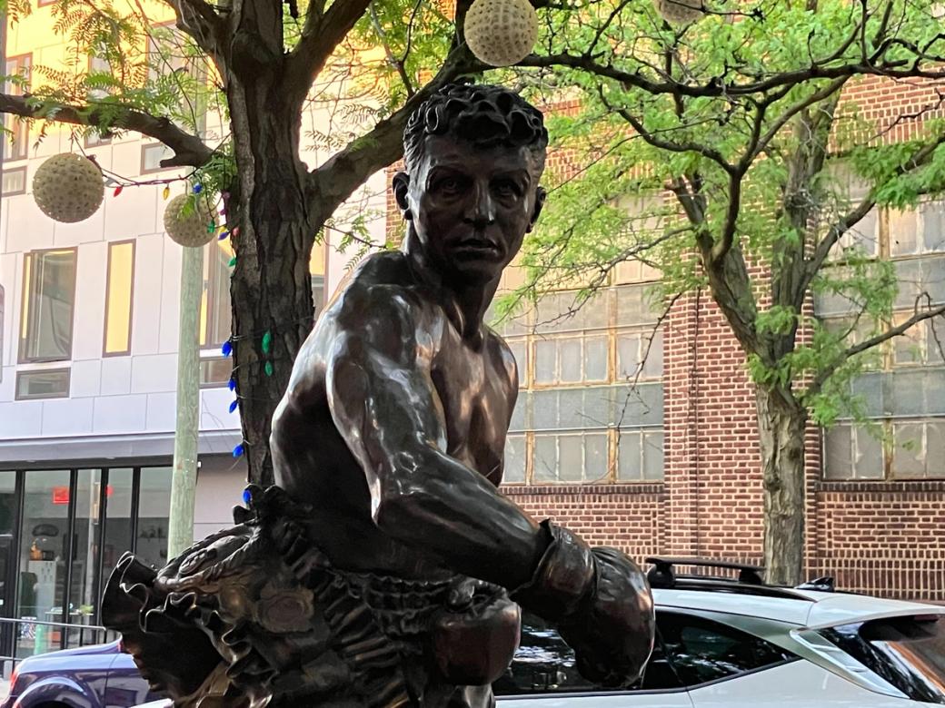A statue of a boxer under a tree