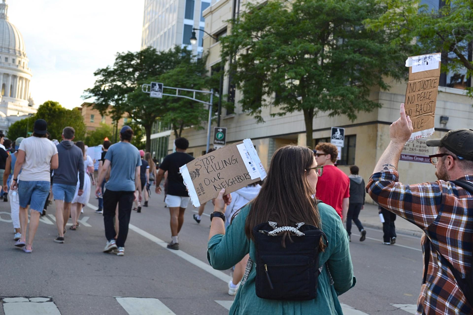 Protesters march down a street holding signs.