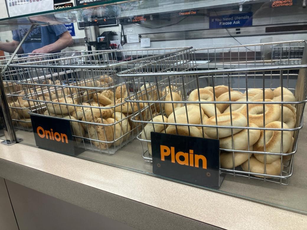 Metal racks of bagels on a counter. 