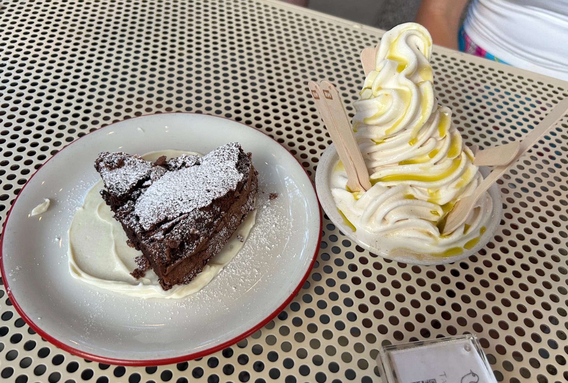 A plate with a chocolate torte and a bowl of vanilla soft serve.