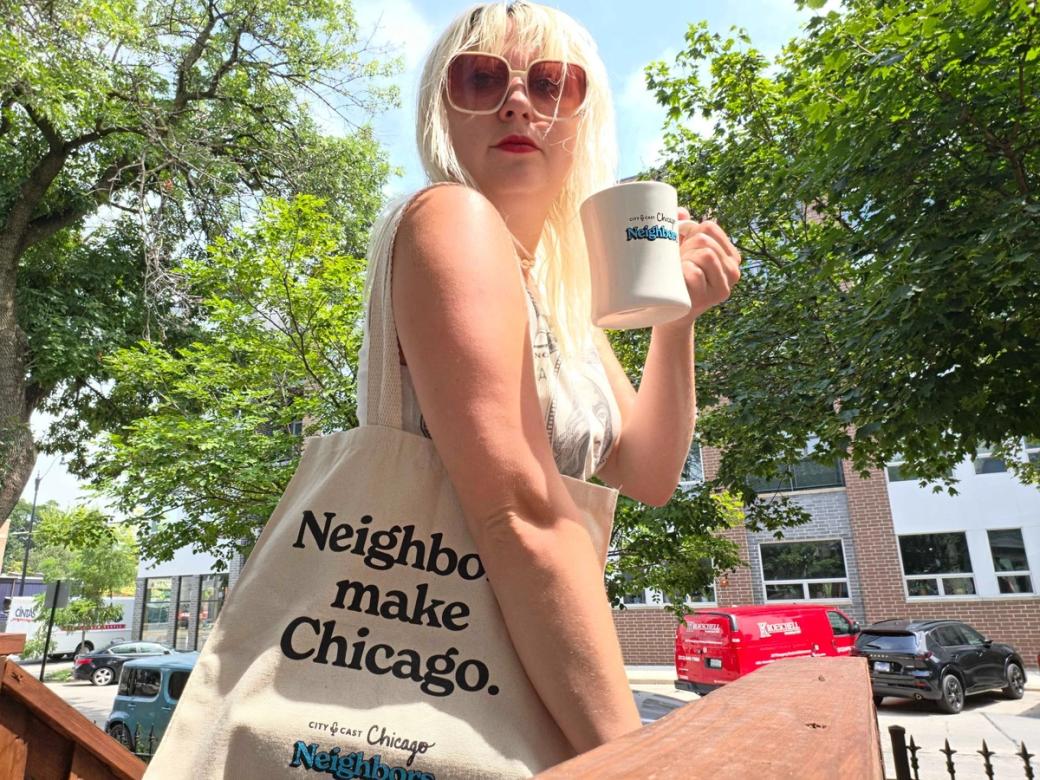 A woman in sunglasses with a tote bag that says "neighbors make Chicago" also holding a mug