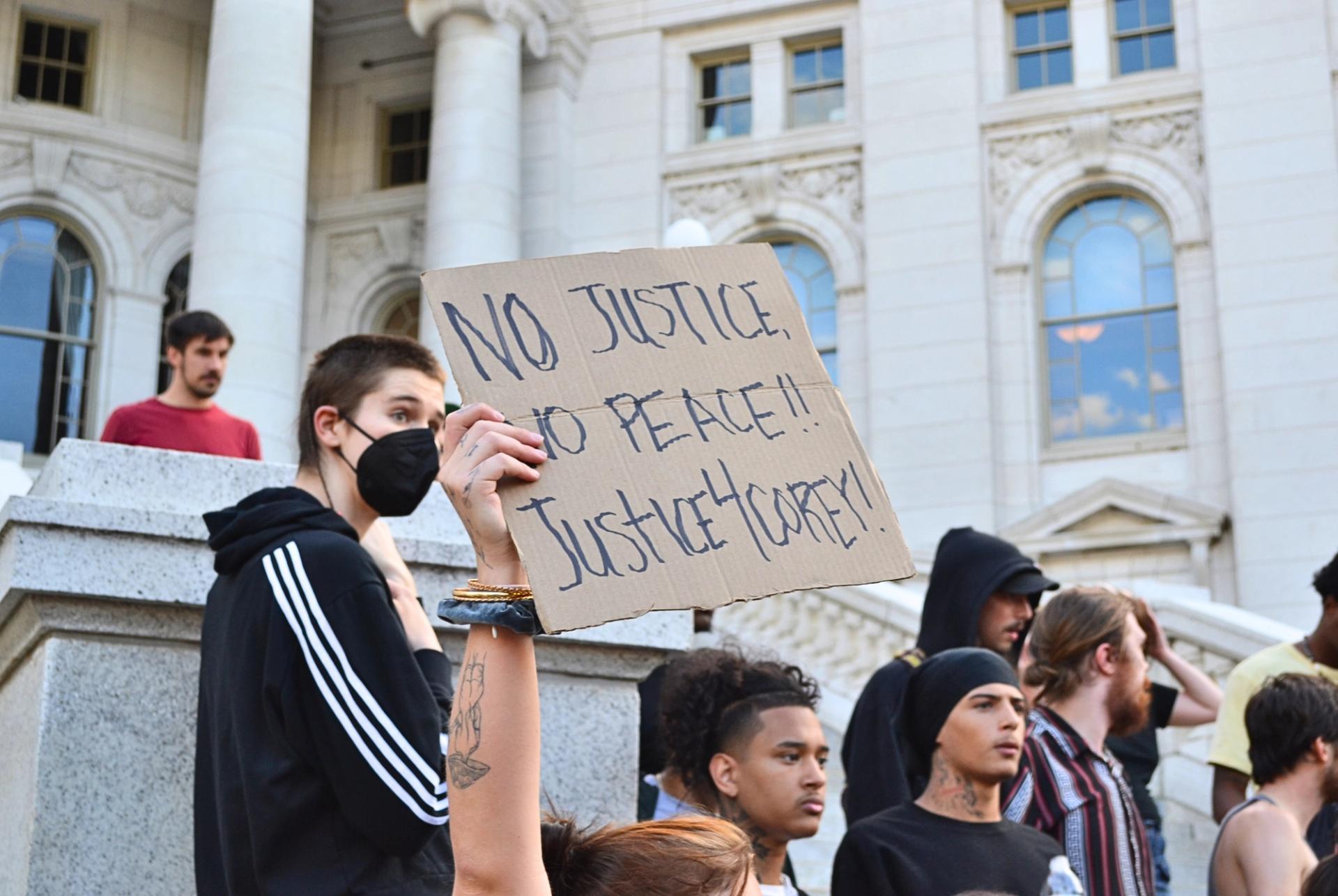 Protesters gather next to a marble building.