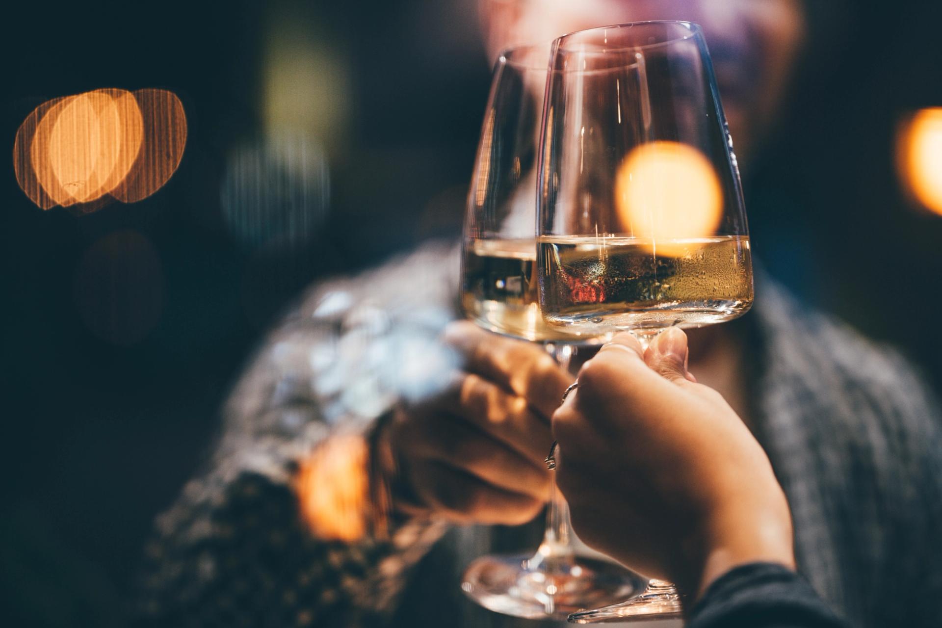 Romantic photo of two hands holding wine glasses.