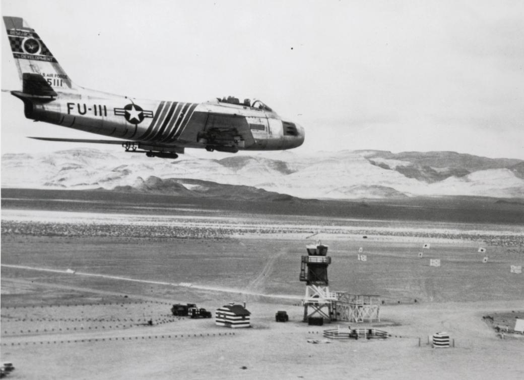 A vintage photo of a plane above Nellis Air Force Base. 