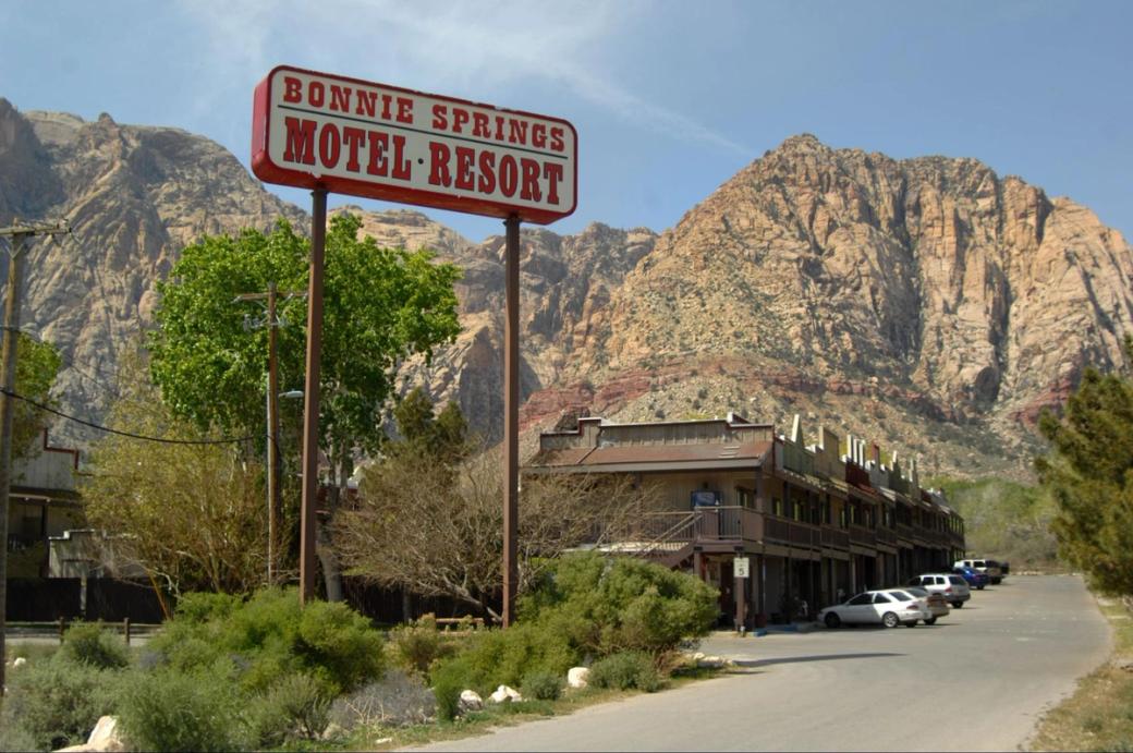 A building up against desert mountains with a sign that reads "Bonnie Springs Motel Resort."