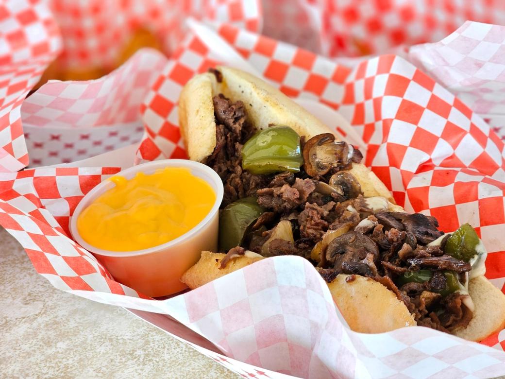 A cheesesteak with cheese on the side.