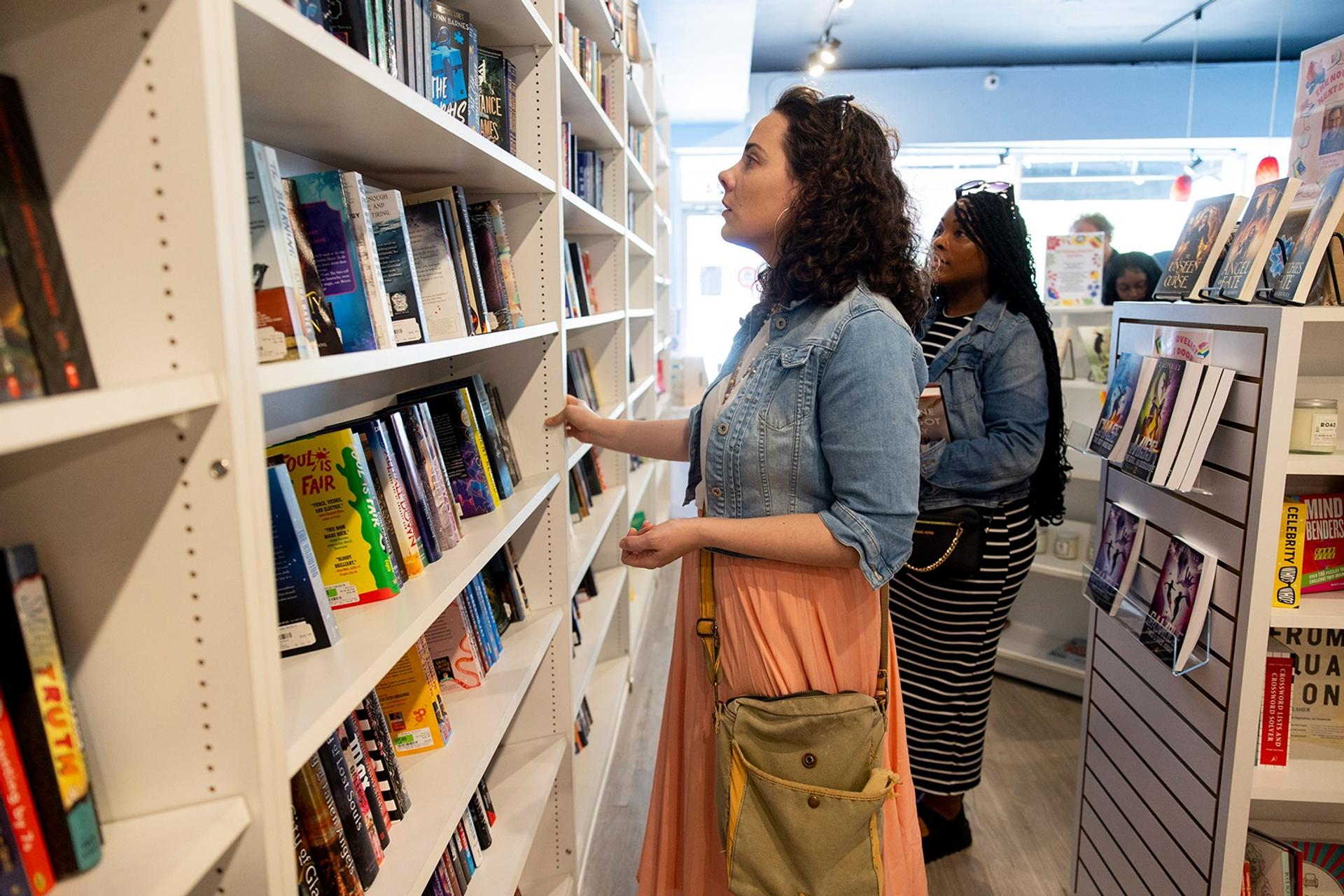 A woman inside of a library browsing books