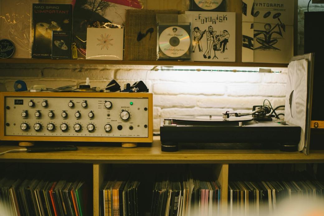 A record player sits on a shelf filled with vinyl records. CDs are displayed above.