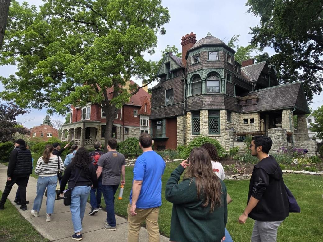 People walking on a sidewalk in front of a house