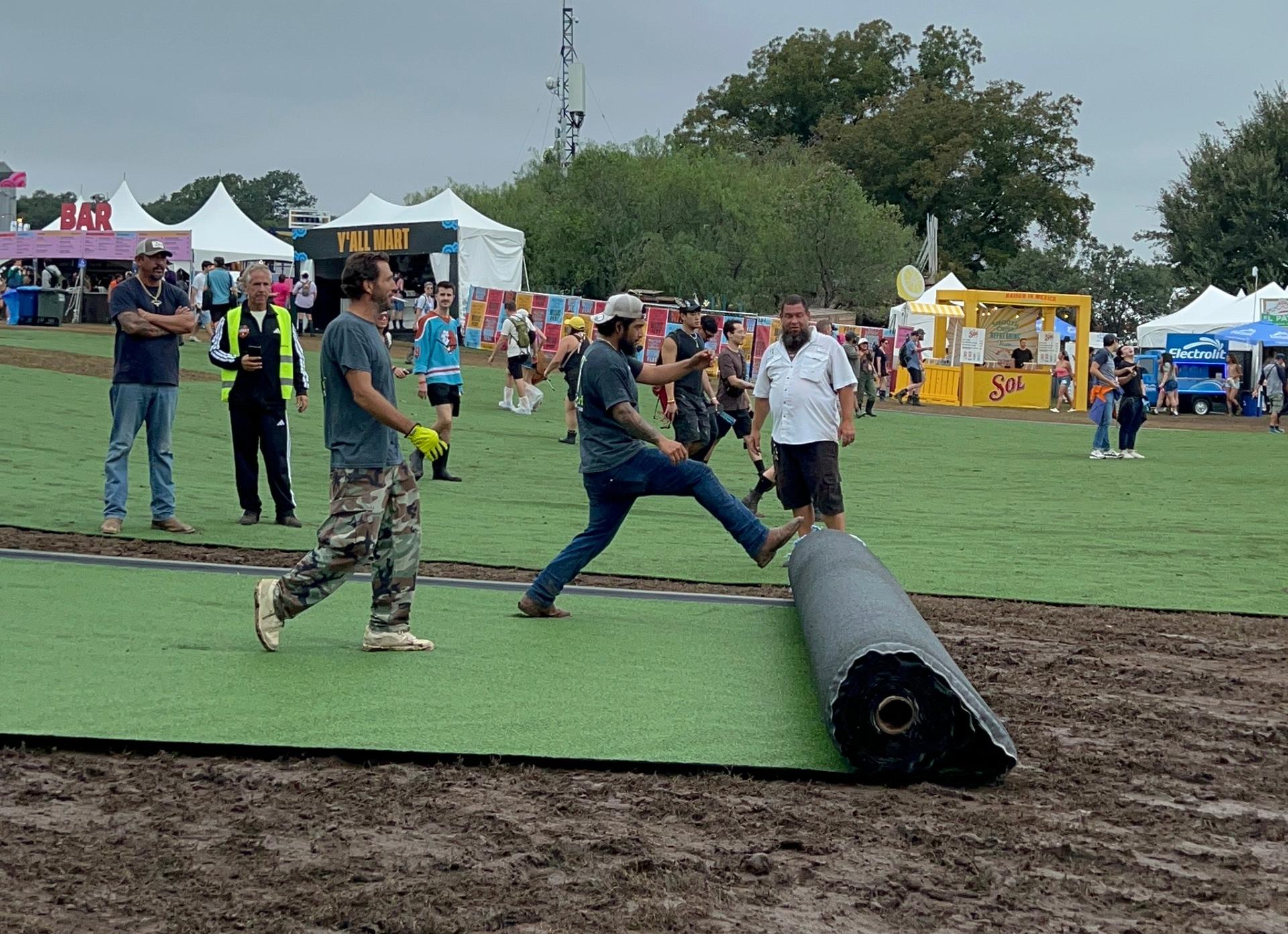 People rolling out artificial turf.