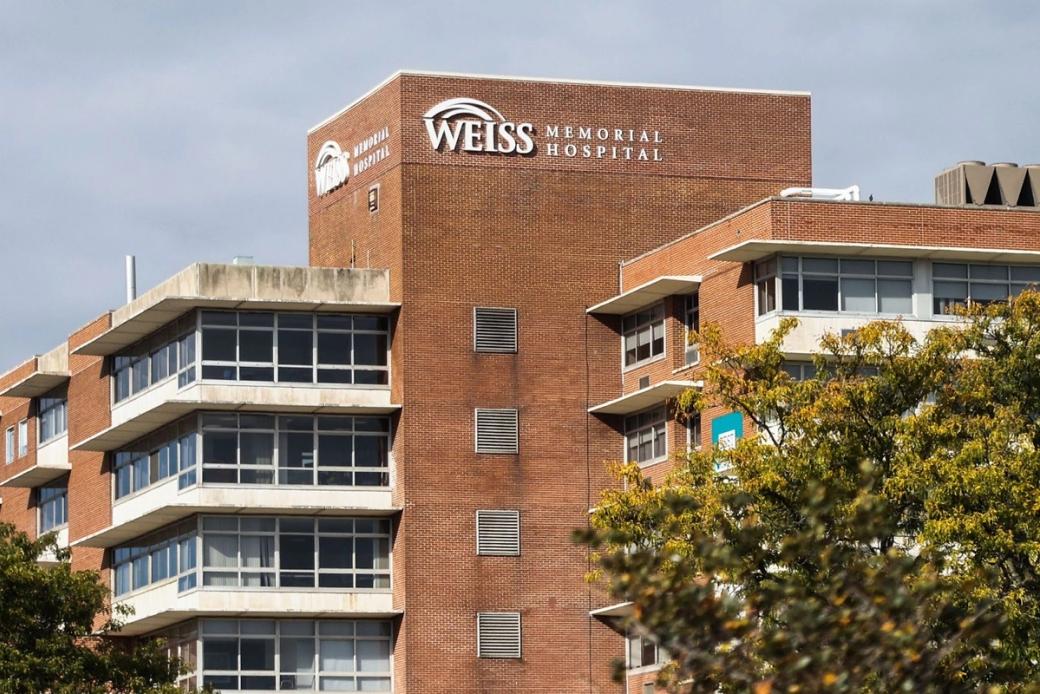 Exterior shot of large brick building with two trees in lower foreground on overcast day