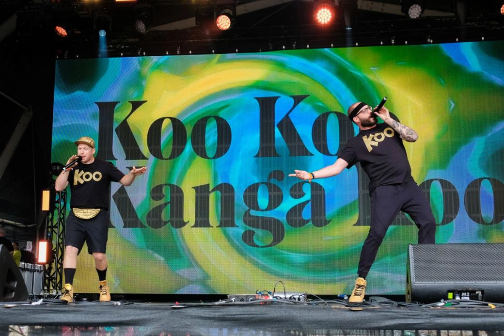 Two men perform into handheld microphones on a stage