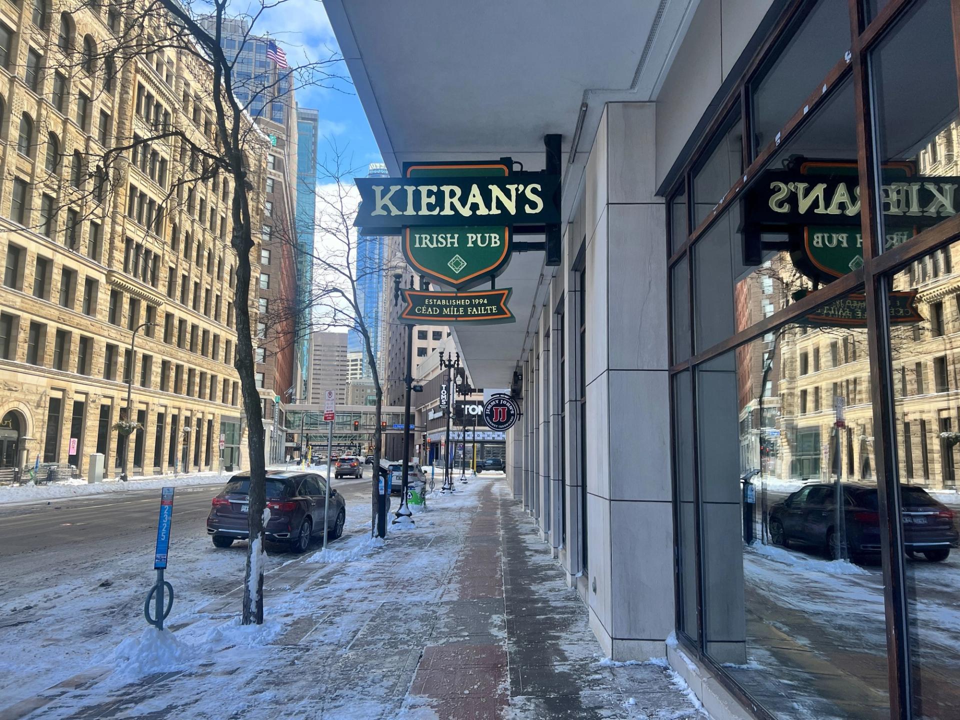 A pedestrian view of a street. A sign reads "Kieran's Irish Pub"