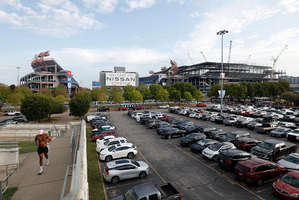 Another stadium being constructed right beside another stadium that says Nissan Stadium. A packed parking lot is in front of both.