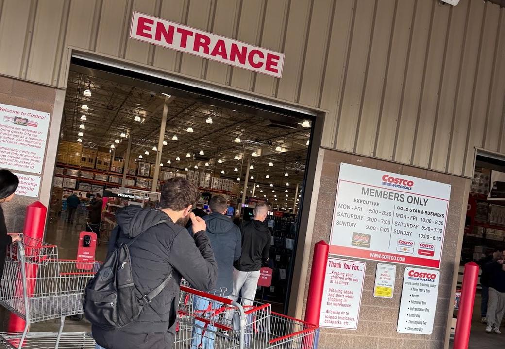A man and a woman with shopping carts under a red entrance sign at the Costco in Seattle