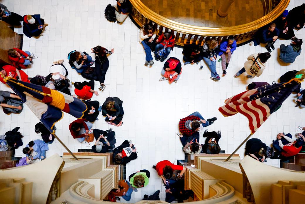 photo of students taken from above at the state capital, an american flag and a colorado flag flank them
