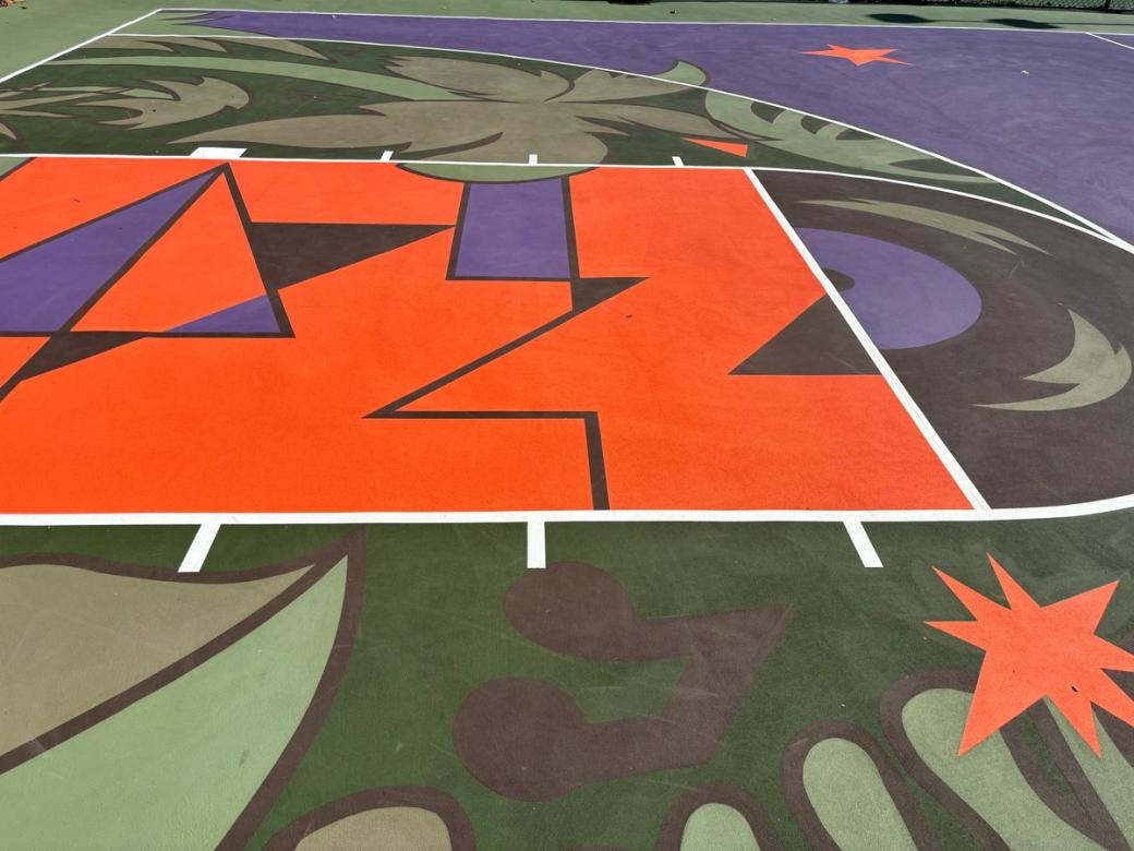 A court floor with abstract designs in green, orange, and purple, featuring images of music and nature.