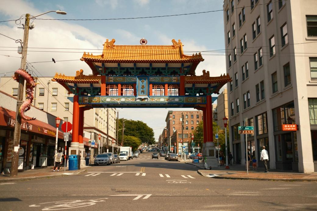 The Historic Chinatown Gate, also known as a paifang, is a 45-foot-tall landmark in Seattle's Chinatown-International District, located on S King Street and 5th Avenue S, with red pillars and a gold roof and a dragon curled around the telephone pole on the left.