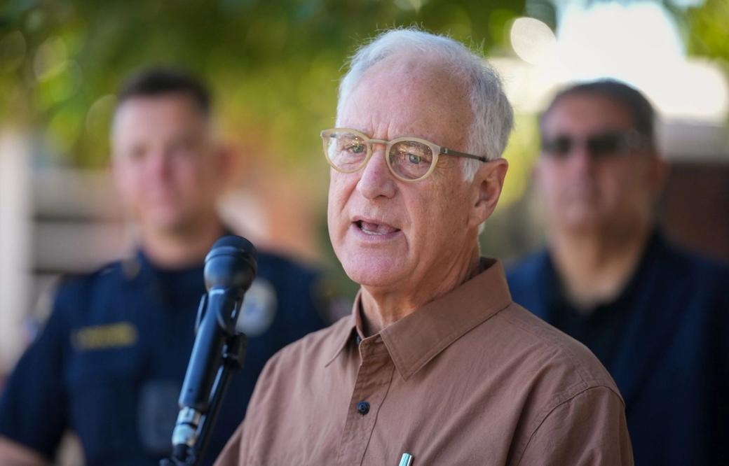 Austin Mayor Kirk Watson stands in front of a microphone outside.