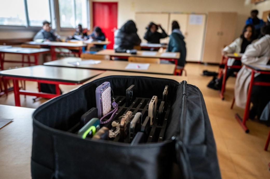 A black bag filled with cell phones in a classroom.