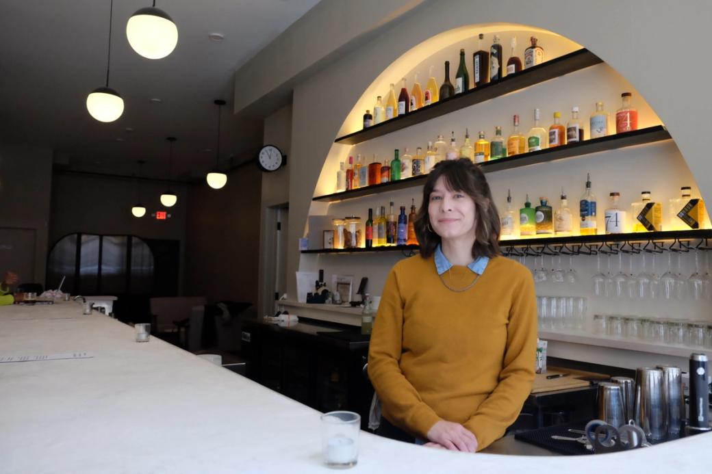 Bartender poses behind bar counter