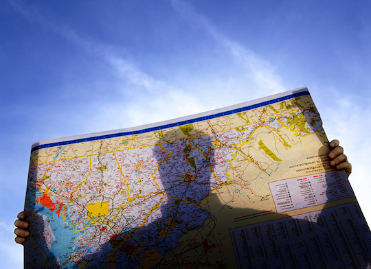 A person's silhouette shown through a map while they're looking at the map