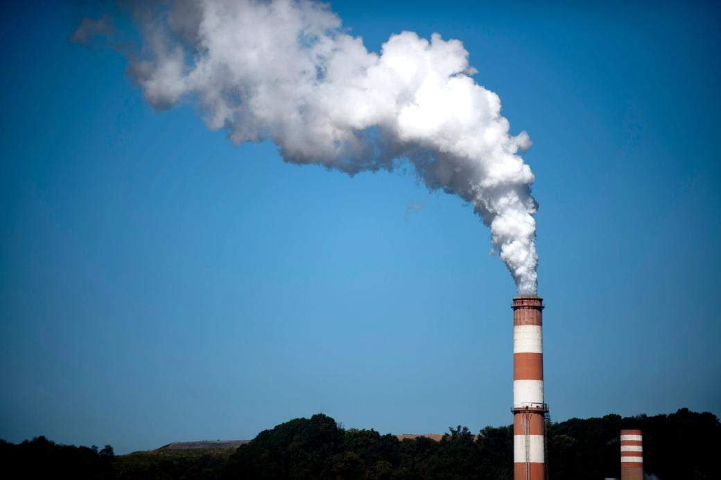 smoke plumes from a red and white smokestack against a blue sky