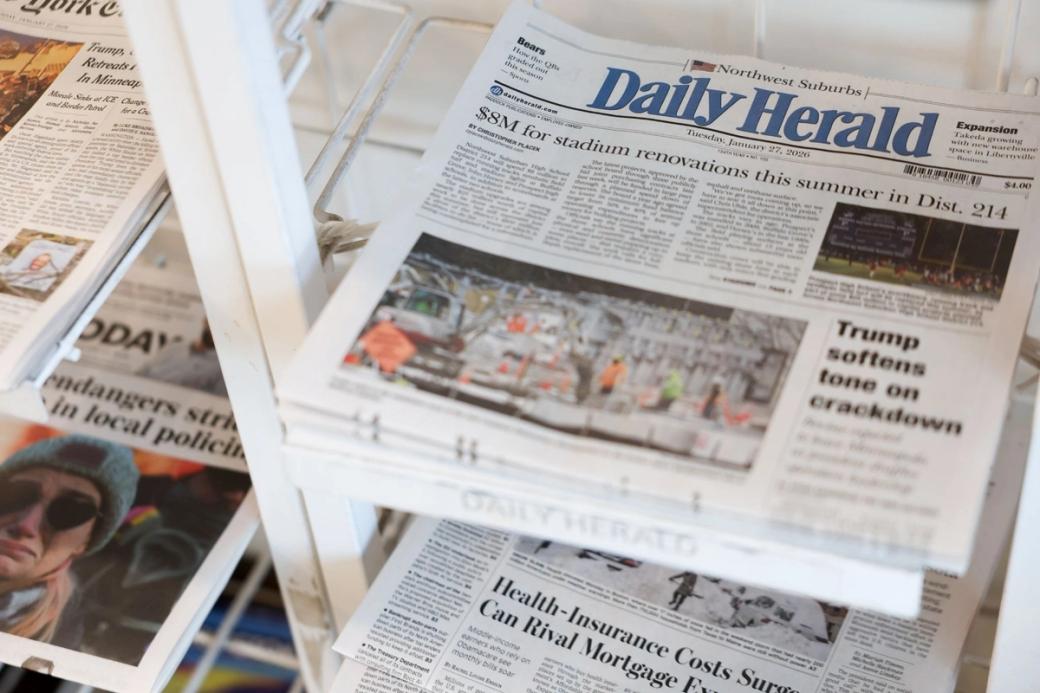A stack of newspapers, the top paper says "Daily Herald"