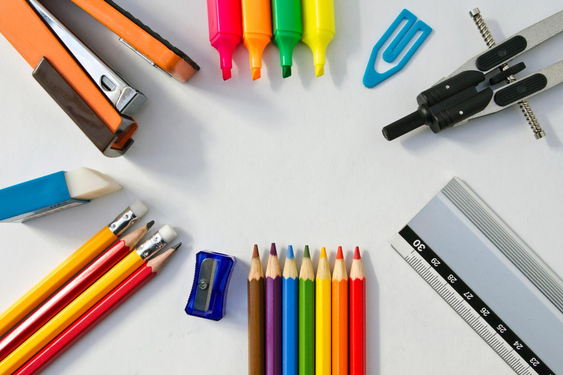 colored pencils, erasers, highlighters and other school supplies sit on a table