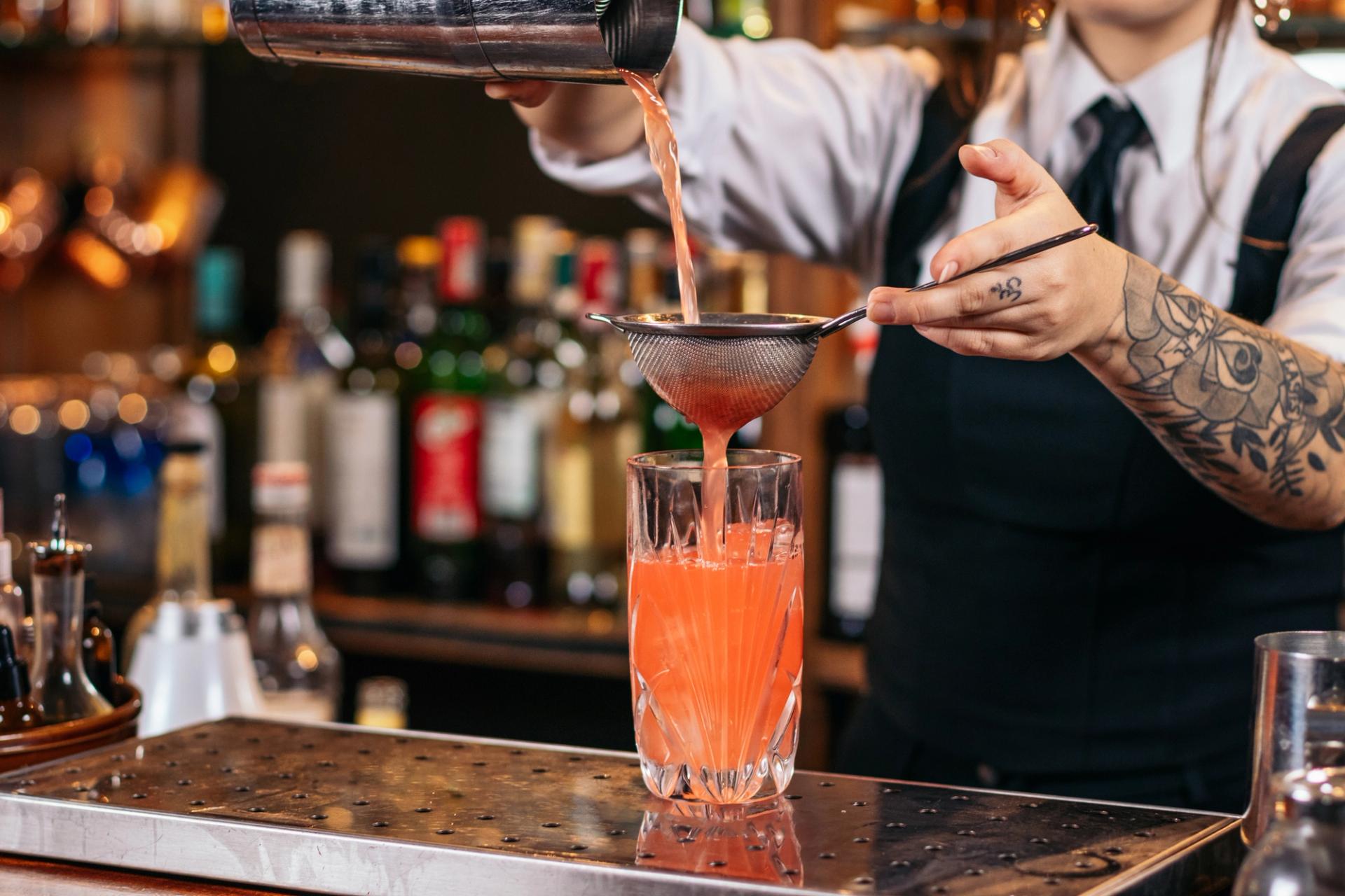 Cutout of a female bartender preparing a cocktail with cocktail shaker in a night pub