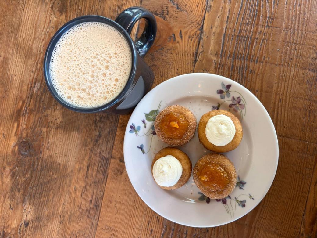 A plate of mini doughnuts and a mug of cider.