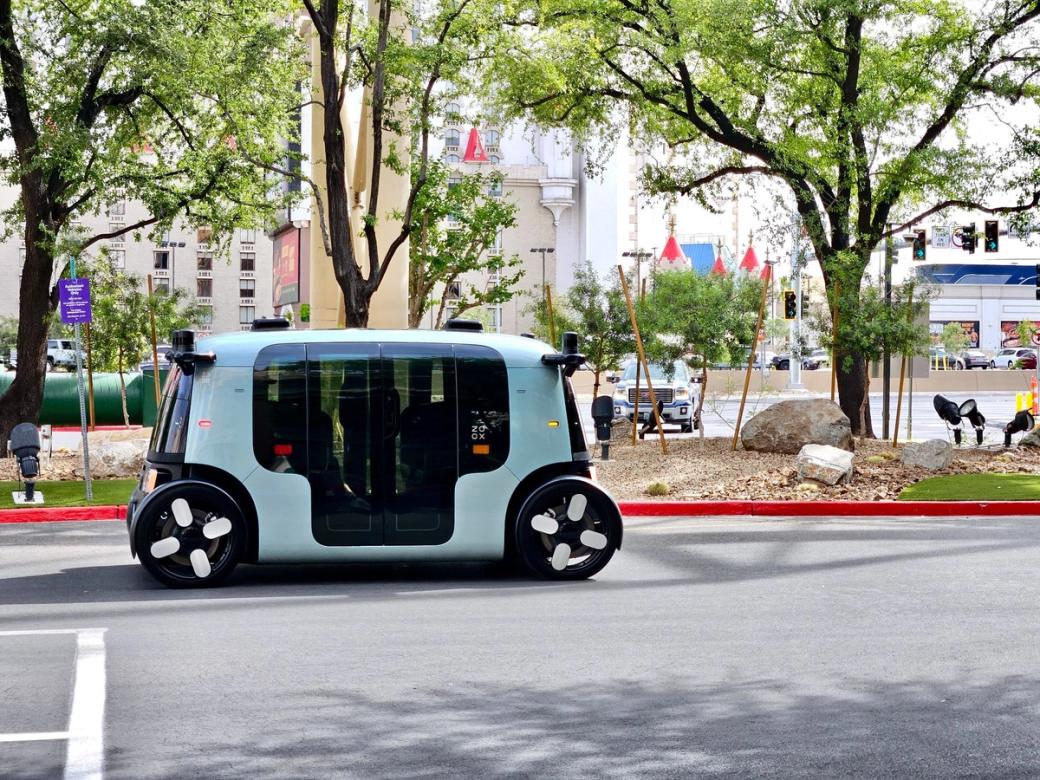 A cornflower blue driverless cart on a tree-lined city street.