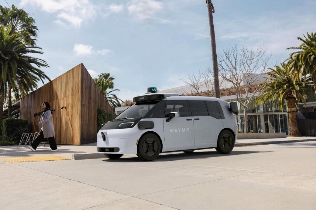 A white Waymo van drives on a city street.