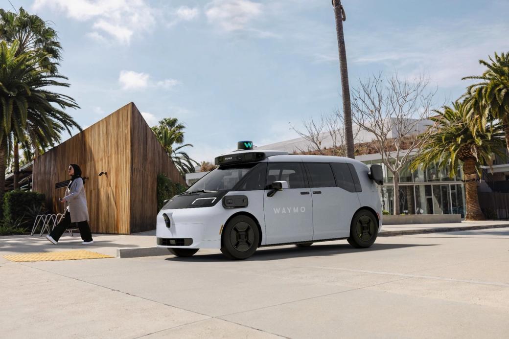 A white Waymo van drives on a city street.