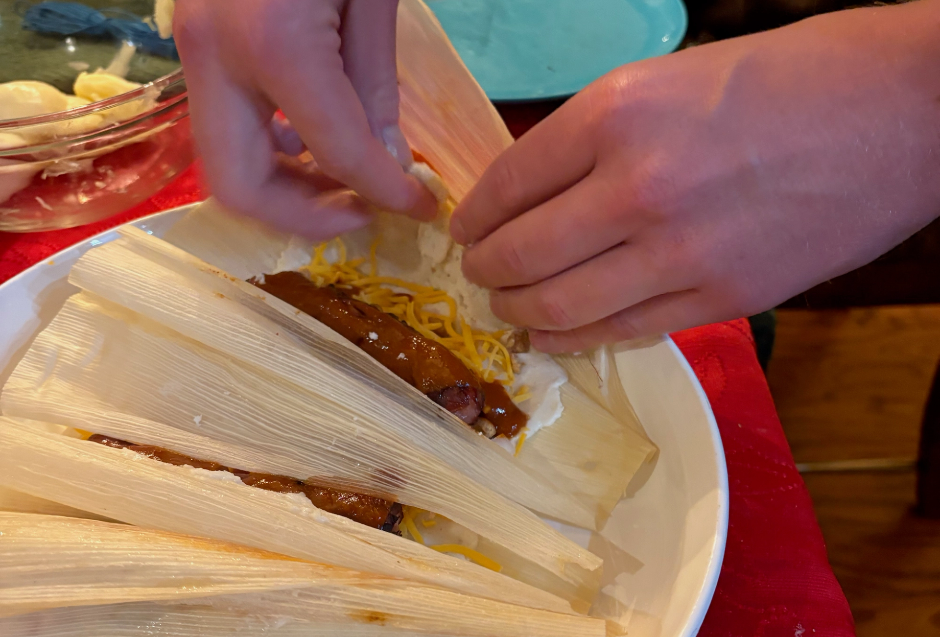 someone slices up a hot dog stuffed tamale