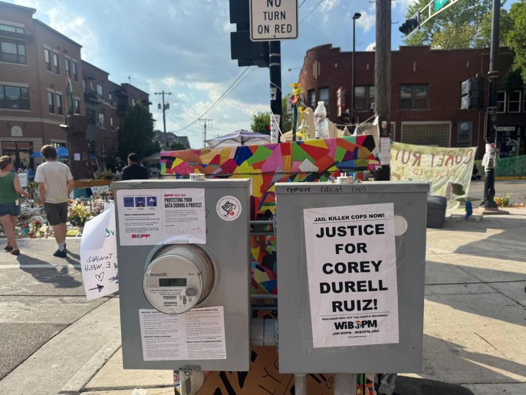 Utility boxes are covered with flyers saying "Justice for Corey Durrell Ruiz!"