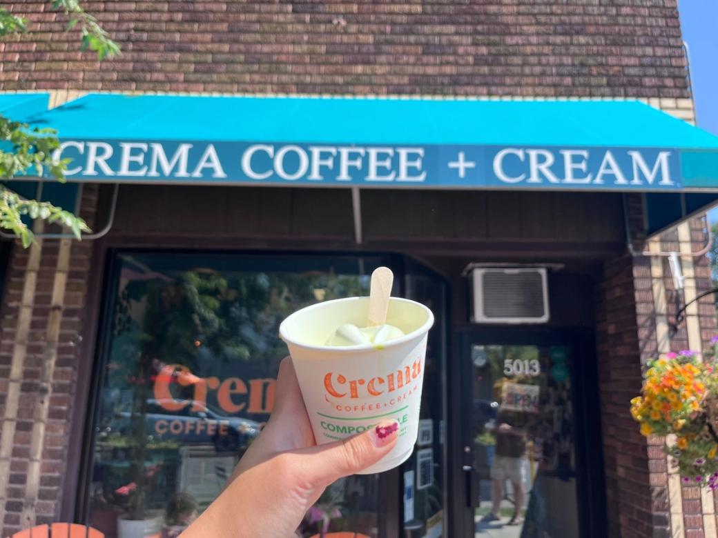 Hand holding a cup of affogato in front of Crema Coffee.