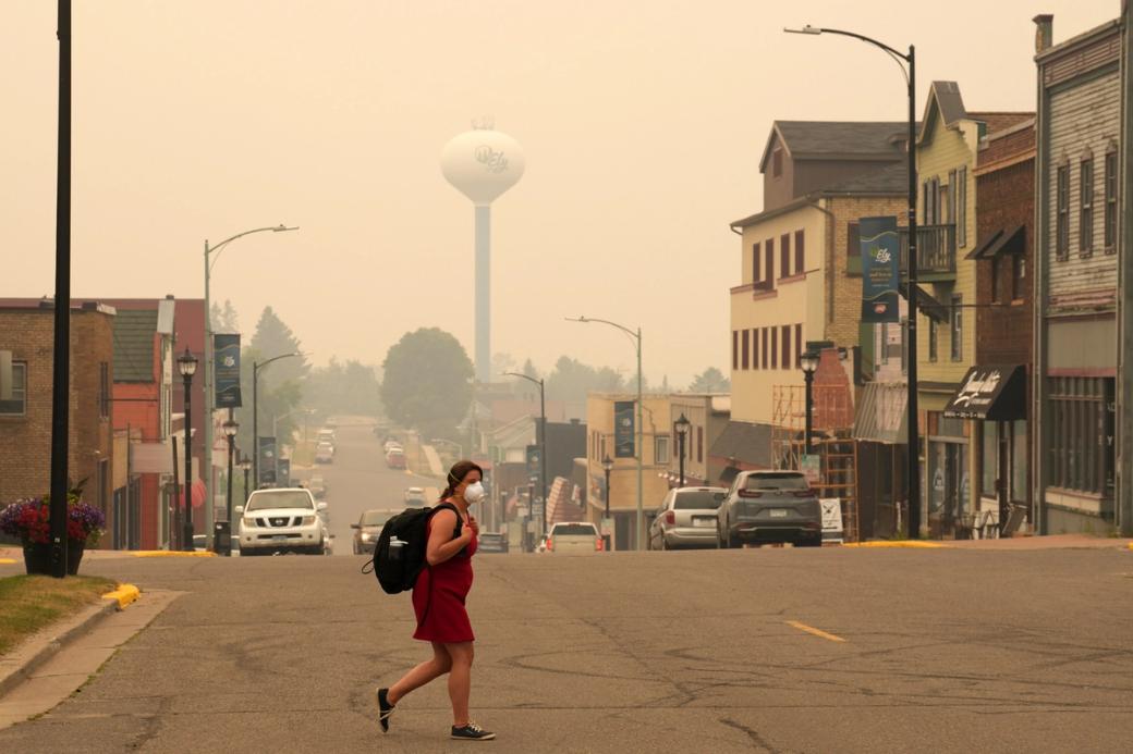 A pedestrian wears a face mask as smoke fills the air in downtown Ely, Minn.