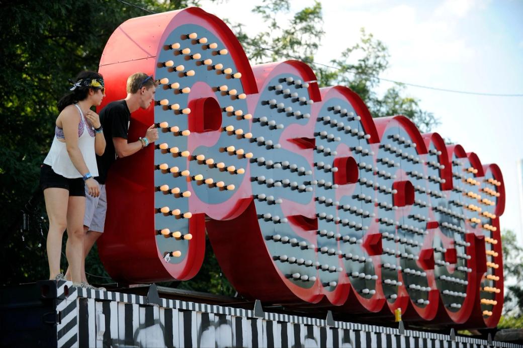 Two people standing on a platform next to a light up sign that says "Perry's"