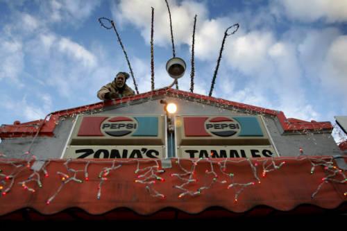Perry Ayers hangs holiday lights on the roof of Zona's in Five Points on Dec. 13, 2004.