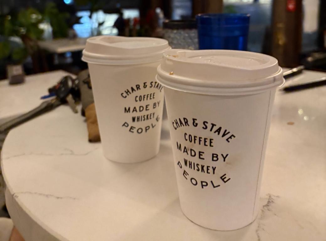 Two white coffee cups with the label “Char & Stave Coffee Made by Whiskey People” on a white table.