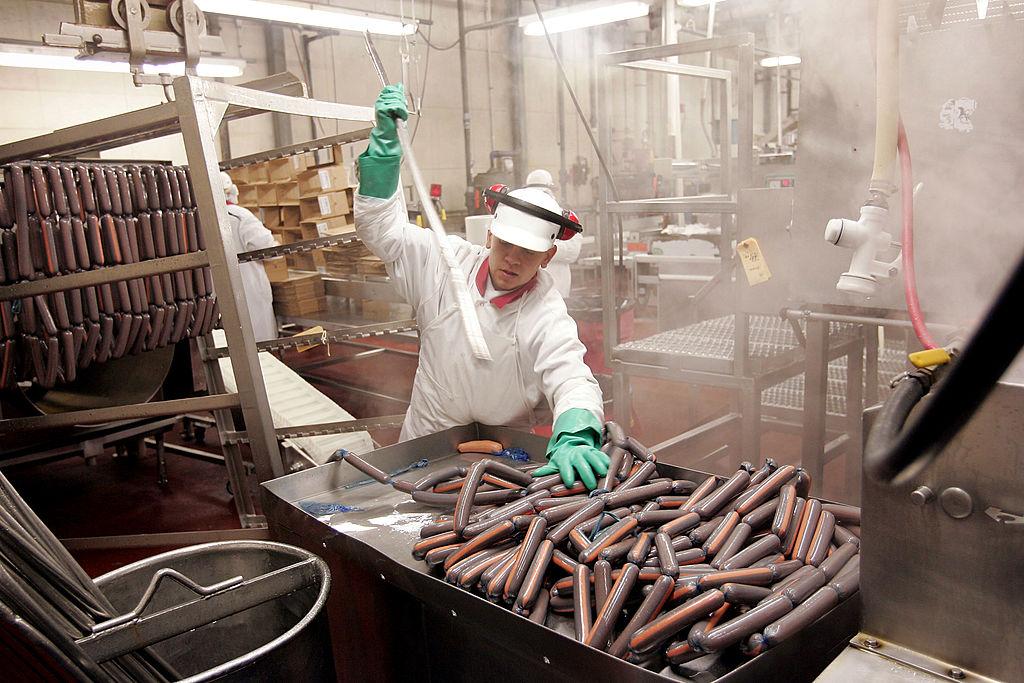 A person in white works on sausages at the Vienna Beef factory in Chicago, Illinois.